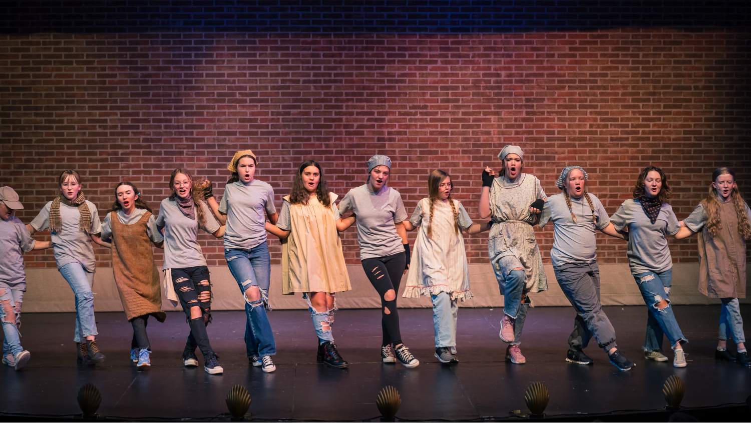 Photo of a group of young performers on stage holding hands