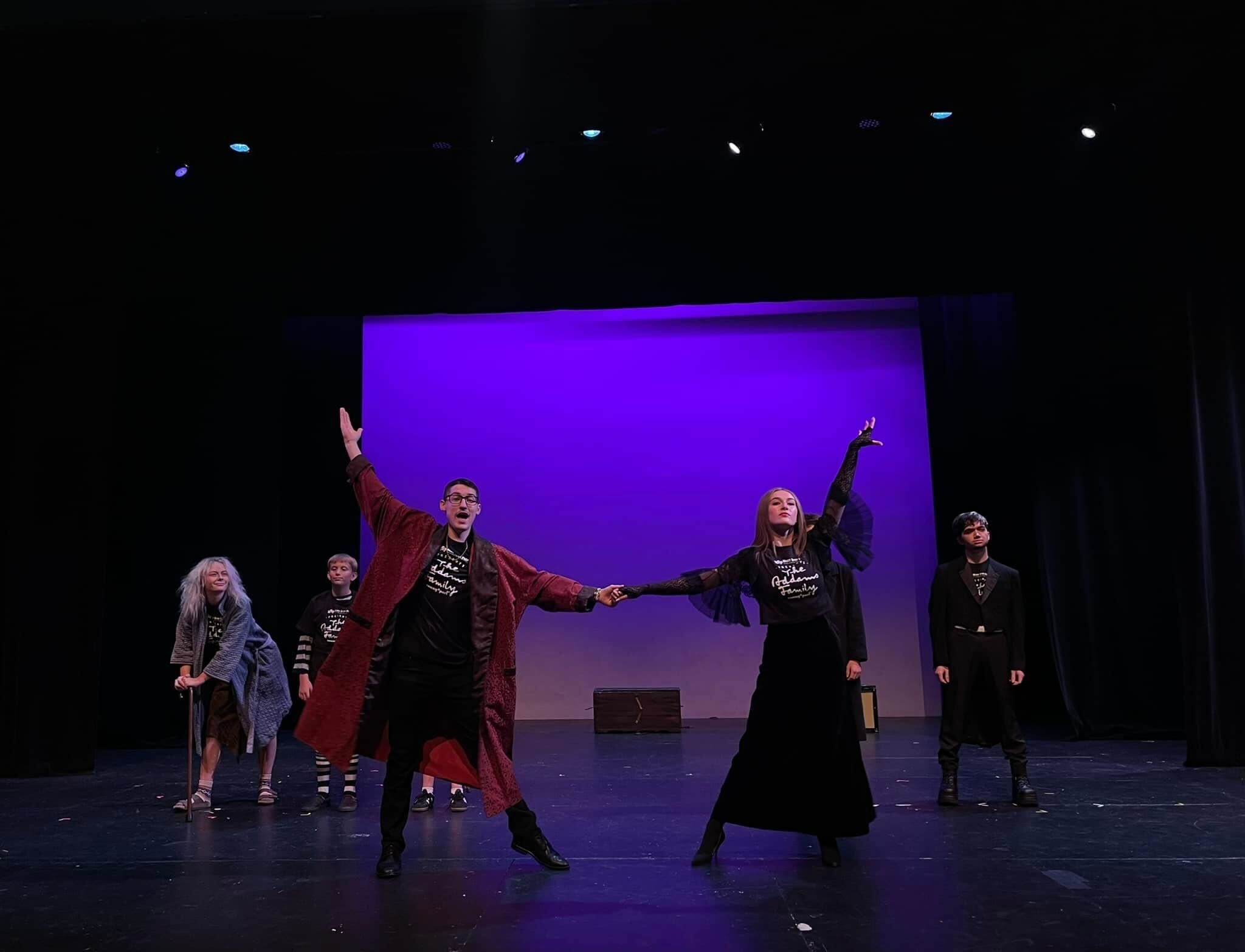 Young performers performing the Addams Family on stage.