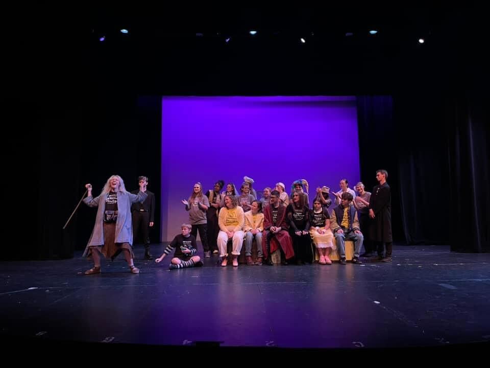 Young performers performing the Addams Family on stage.