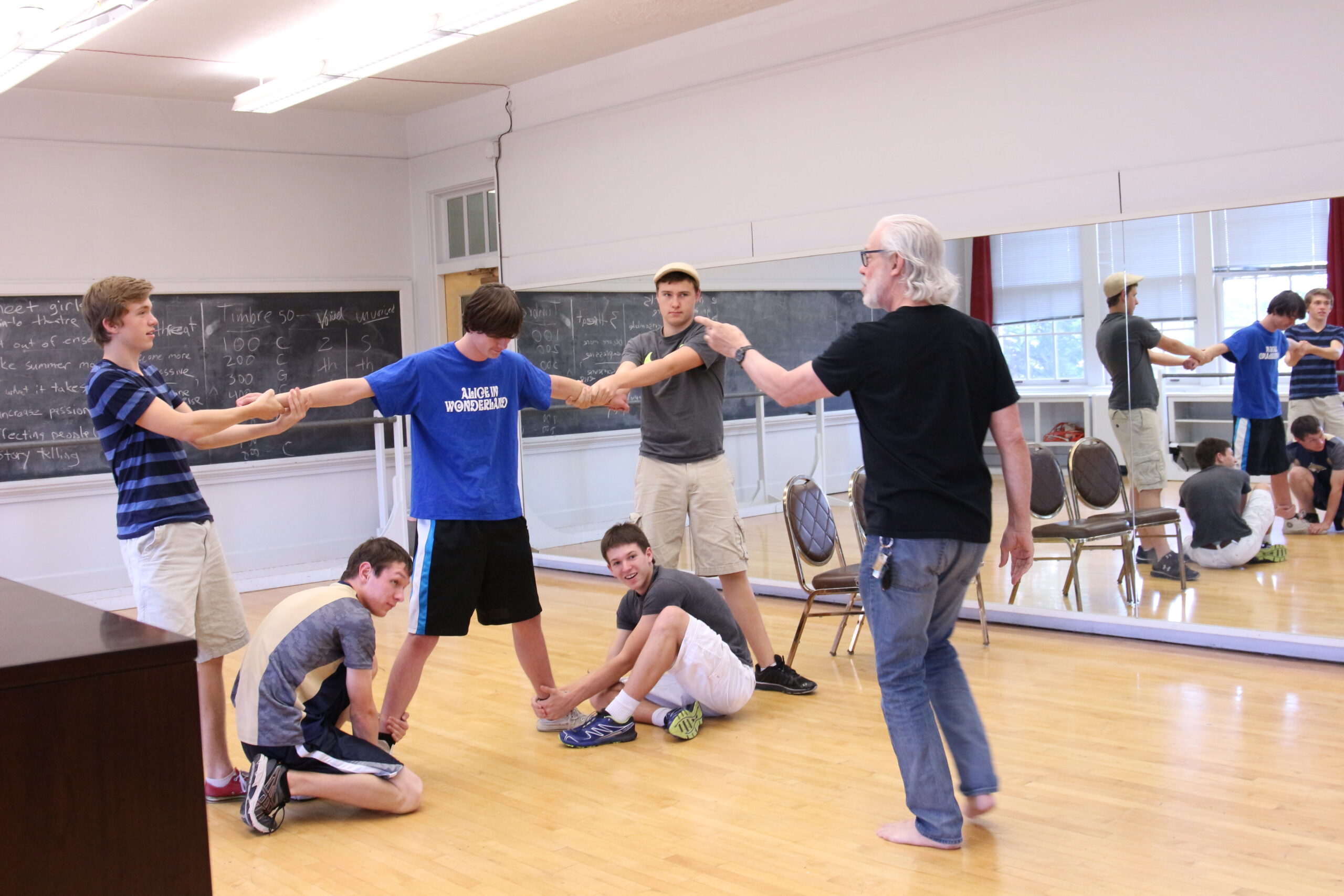 Group of students and a teacher rehearsing in a classroom