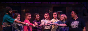 Group of young performers on stage holding their wands in the middle of a circle.
